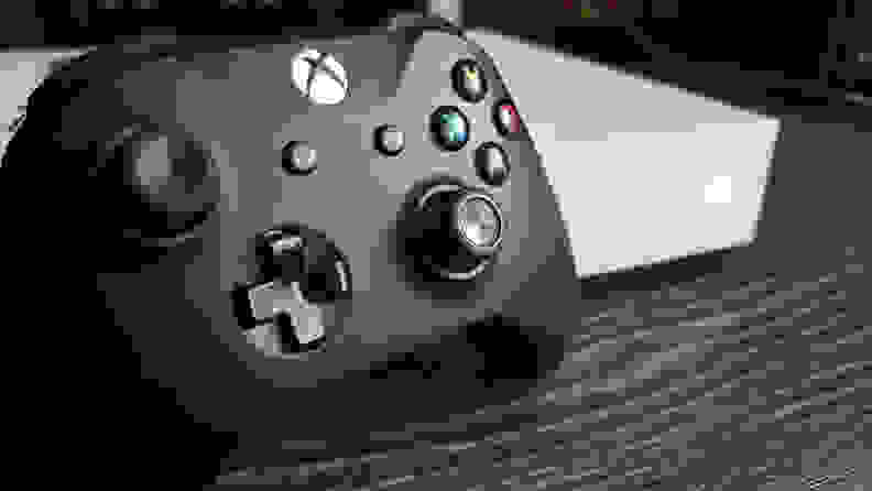 An Xbox controller sitting on a table next to an Xbox console