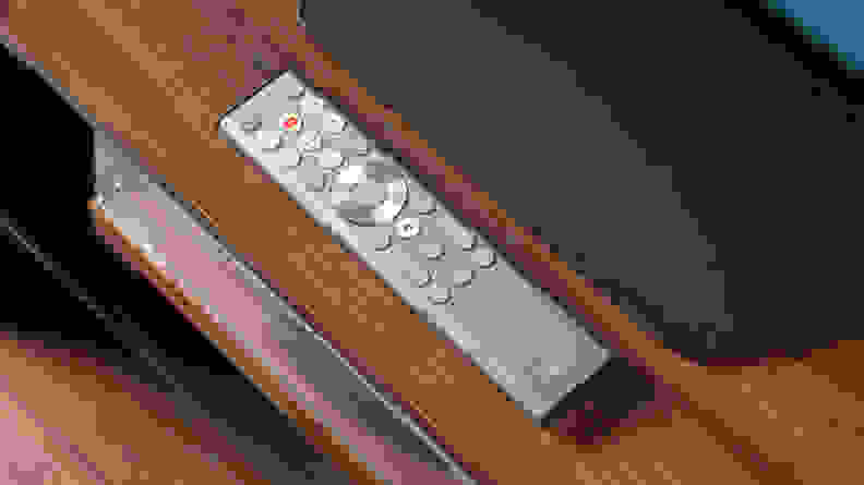 The Hisense U8N's chrome-accented remote control placed on a wooden media console in front of the TV's stand