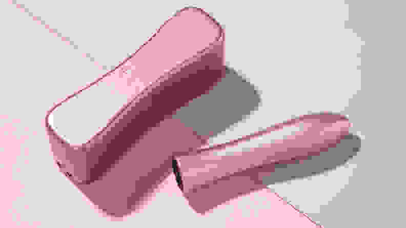 A pink Bougie Bullet vibrator next to its hardshell travel case on top of a pink and purple background.