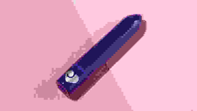 A dark purple Lovehoney Magic Bullet Vibrator on a diagonal angle on top of a two-tone pink background.