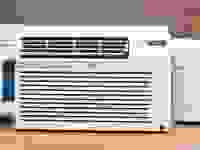 Three of the best window air conditioners are displayed on a wooden countertop, all are white.