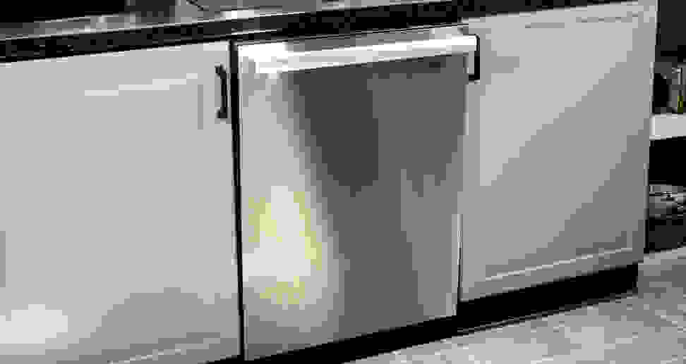 A close-up shot of a stainless steel dishwasher installed into a kitchen cabinet.