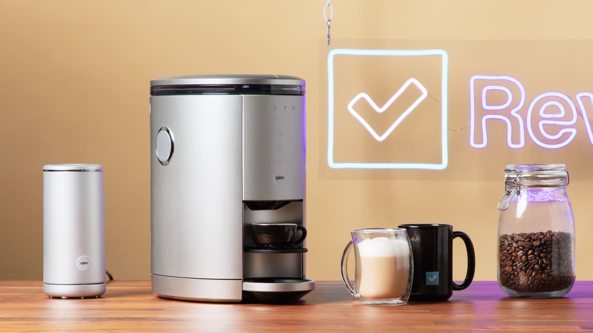 A smart Spinn Coffee maker surrounded by coffee cups and coffee grounds.