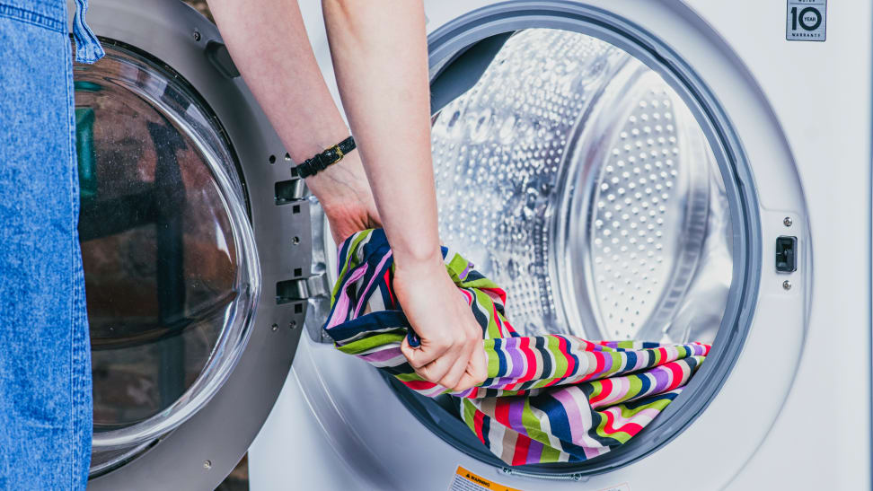 A person removing clothes from a front-load washer.