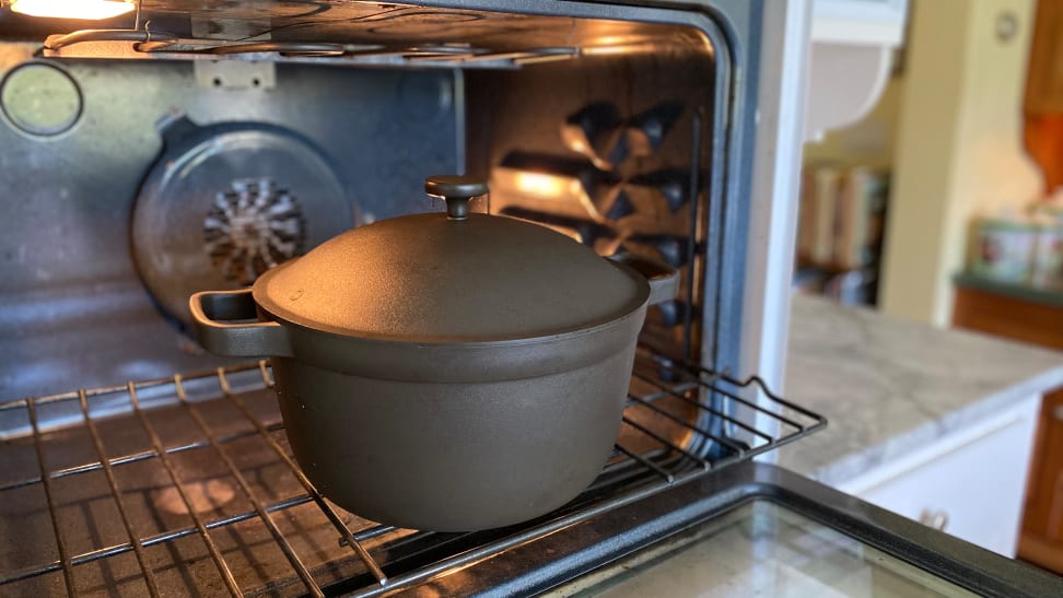 A person is pulling an oven rack, which has the Perfect Pot in gray color on it.