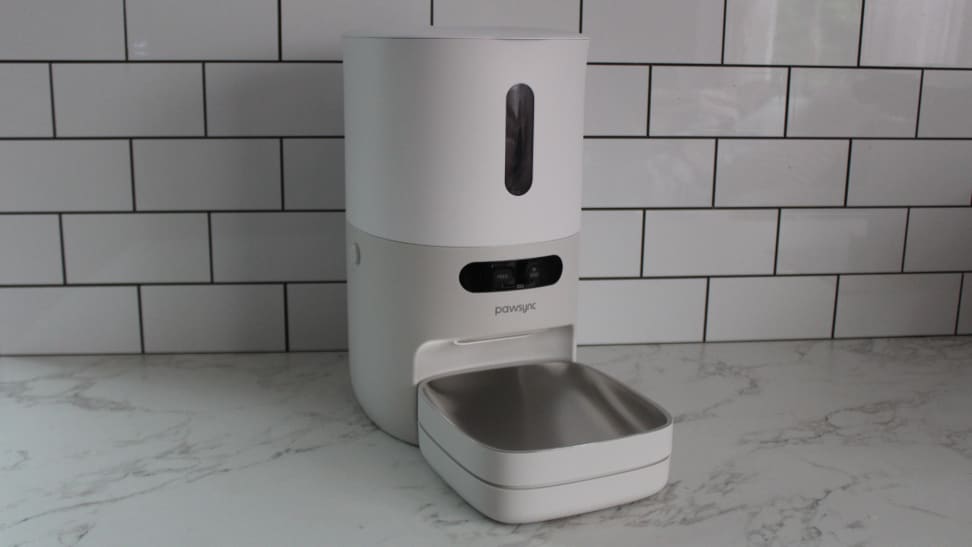 The PawSync Smart Pet Feeder on a marble countertop in front a tiled wall.