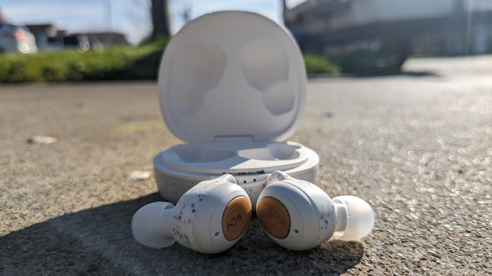 House of Marley Champion 2 earbuds outside the headphones case, on concrete.