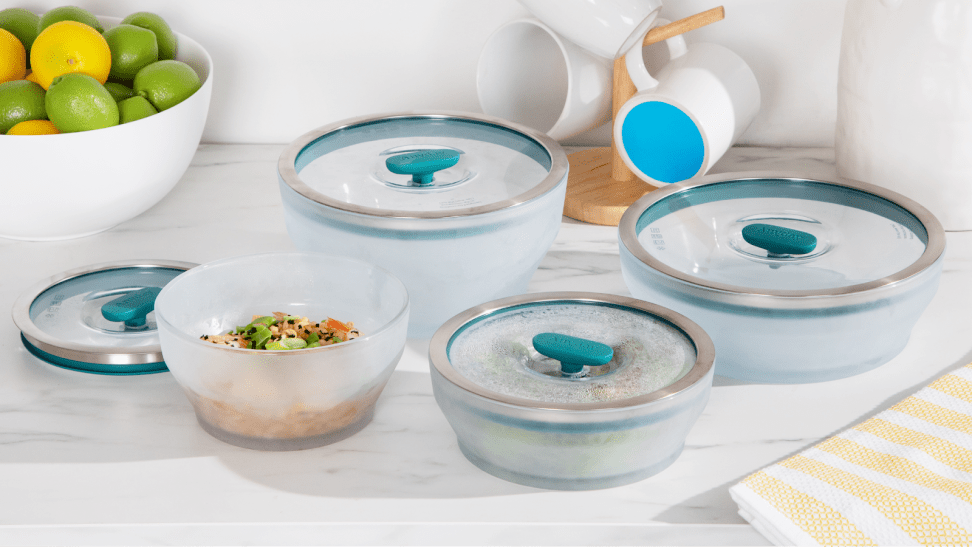 Four pieces of Anyday cookware laid out on a marble surface, one is open revealing leftover noodles.