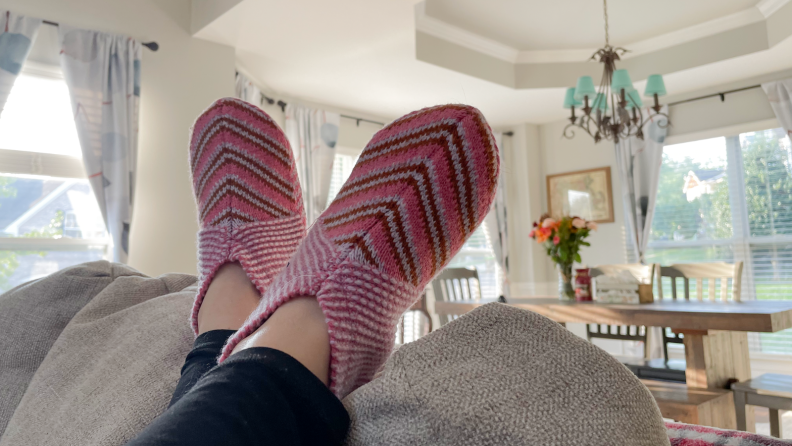 Person wearing Bombas slippers hanging off a couch.