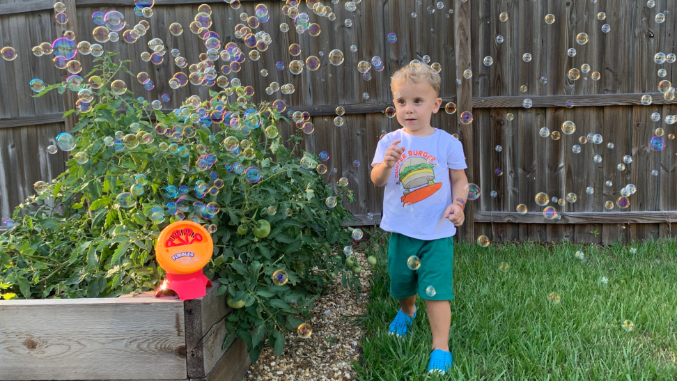 A toddler runs through bubbles outside