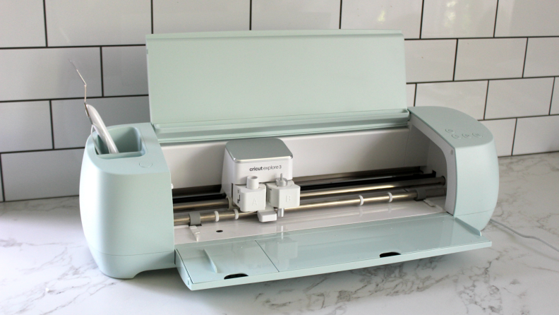 The Cricut Explore 3 in a mint color opened up to reveal its inner workings.