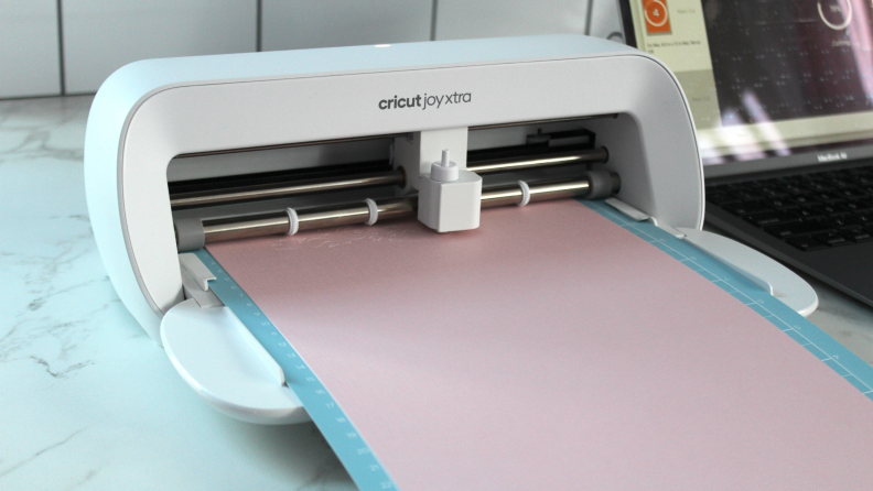 The Cricut Joy Xtra embossing a long strip of pink material.