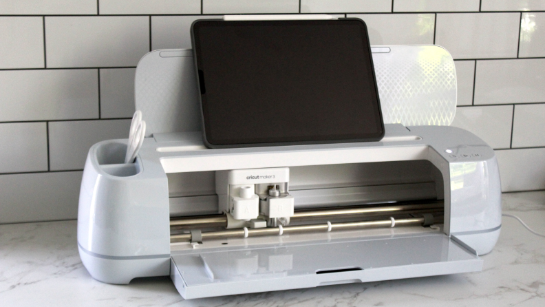 The Cricut Maker 3 in white opened up to reveal its inner workings.