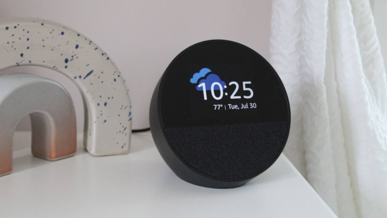 The Amazon Echo Spot on a nightstand, displaying the time and weather.