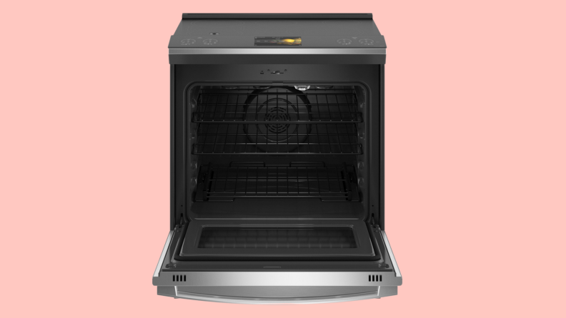 An open stainless steel oven against a pink background.