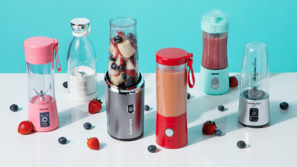 Six portable blenders sit on a white surface surrounded by berries.