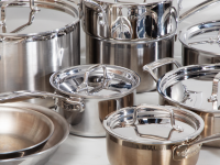 Several stainless steel pots and pans crowded together on a white surface