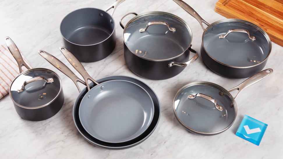 Several pieces of cookware on a white marble countertop, beside a Reviewed checkmark logo