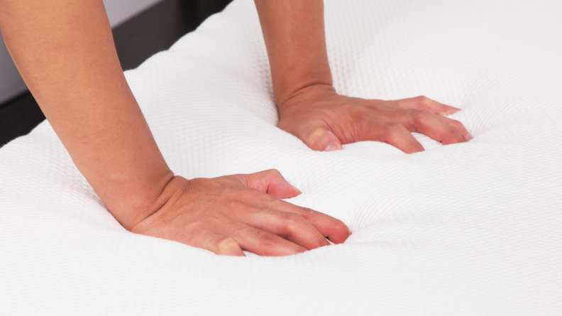 Close up of hands pressing on Essentia Stratami mattress