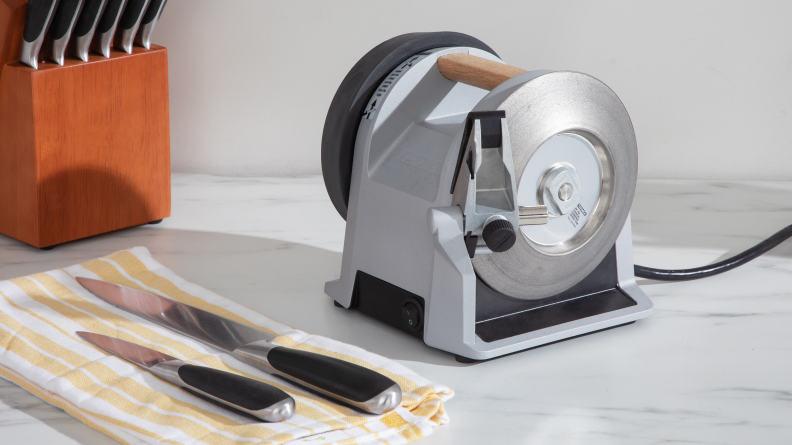 Tormek knife sharpener beside two kitchen knives on a marble surface