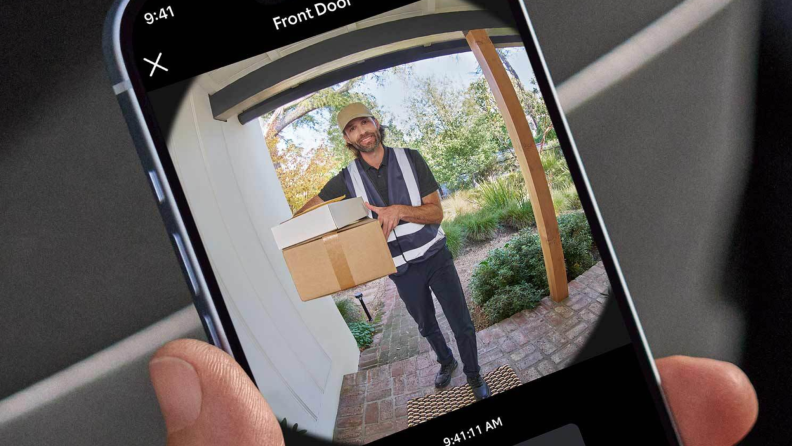 A hand holding a phone that shows the Ring app open to the view from the new Ring Battery Doorbell.