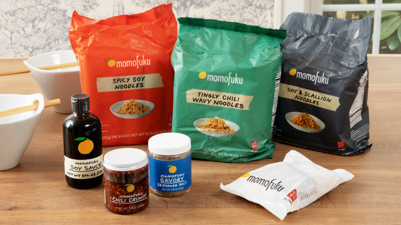 Assorted Momofuku packaged food products on top of wooden surface.