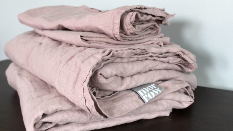 A stack of folded, mauve linen Morrow sheets