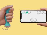 A hand holding the Perifit Care+ perineometer and another hand holding a cellphone with a game onscreen.