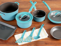 Turquoise blue colored pans, pots, lids and cooking utensils next to small rectangular baking sheet on top of wooden countertop surface.