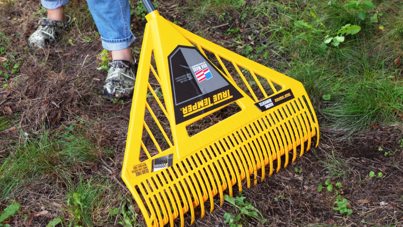 Person uses a Tru Temper leaf rake to gather yard debris.