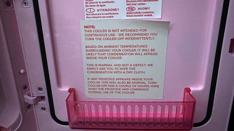 A close-up of a warning label on the inside of a pink thermoelectric cooler. It reads, "Note: This cooler is not intended for continuous use—we recommend you turn the cooler off intermittently. Based on ambient temperatures surrounding your cooler, it will be likely that condensation will appear inside your cooler. This is normal and not a defect, we simply ask you to wipe the condensation with a dry cloth. If any frost/ice appears inside your cooler this will also be normal. Turn cooler off for a couple hours, wipe away the frost/ice and commence normal use of the cooler."