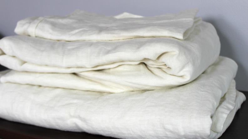 A stack of folded, white Saatva linen  sheets