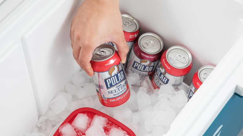 Someone putting a can of seltzer in an ice filled cooler.