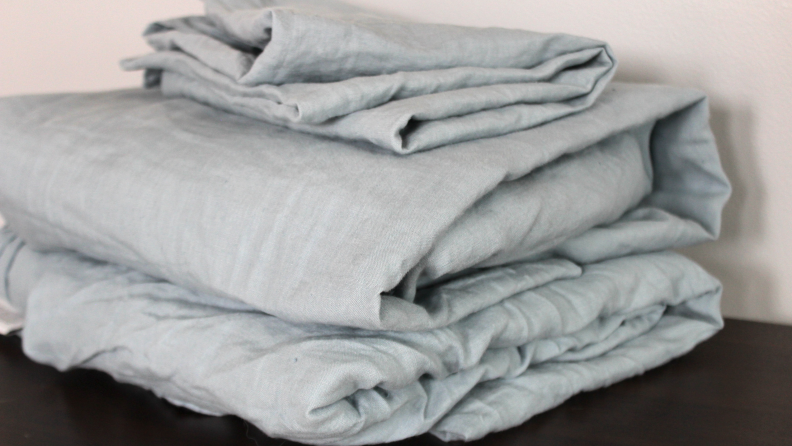 A stack of folded, light blue Tuft & Needle linen sheets