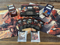 The Star Wars: Unlimited card game, with cards fanned out in front of a deck of cards, cardboard tokens, two deck boxes with images of Luke Skywalker and Darth Vader, the game box with the same images, and a foldable playmat.