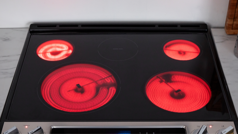 Four cooktop eyes on top of the Whirlpool WEE745H0LZ Electric Range turned on and illuminated red.